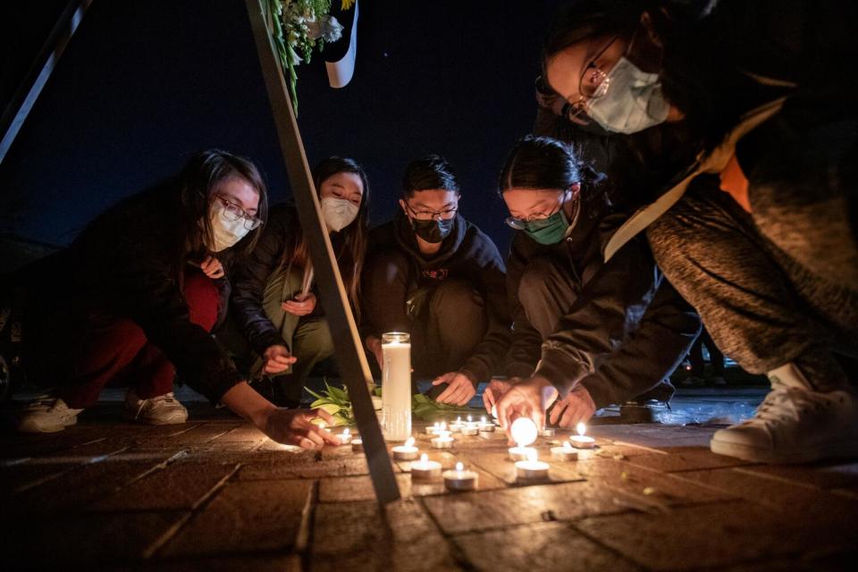 A cluster of candles surrounded by people.