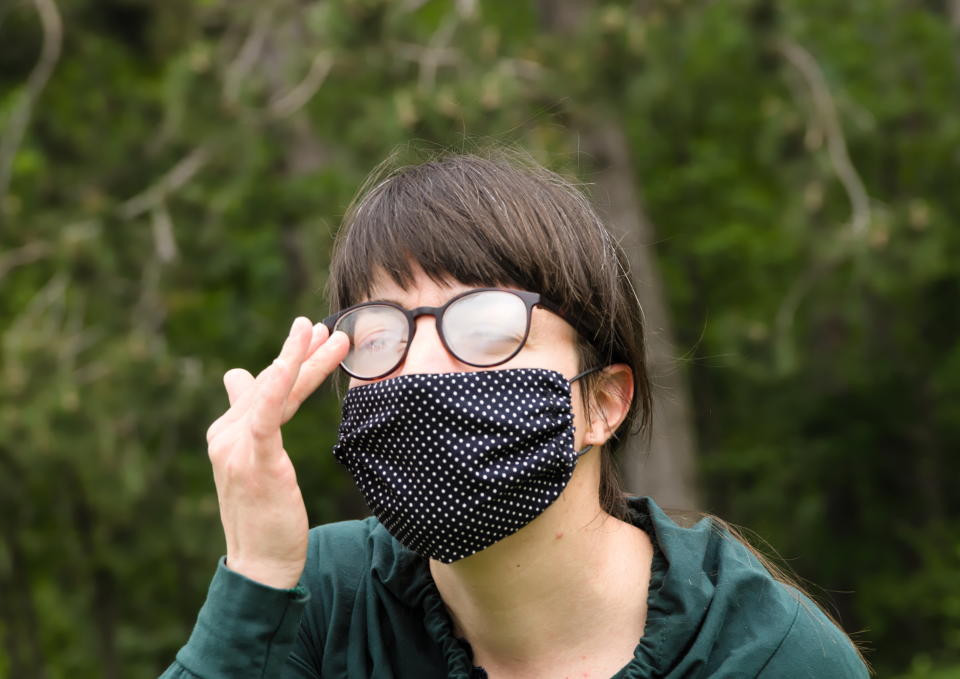 Headshot of Young Adult Brunette Woman Cleaning Fog (Condensed Water) of her Eyeglasses