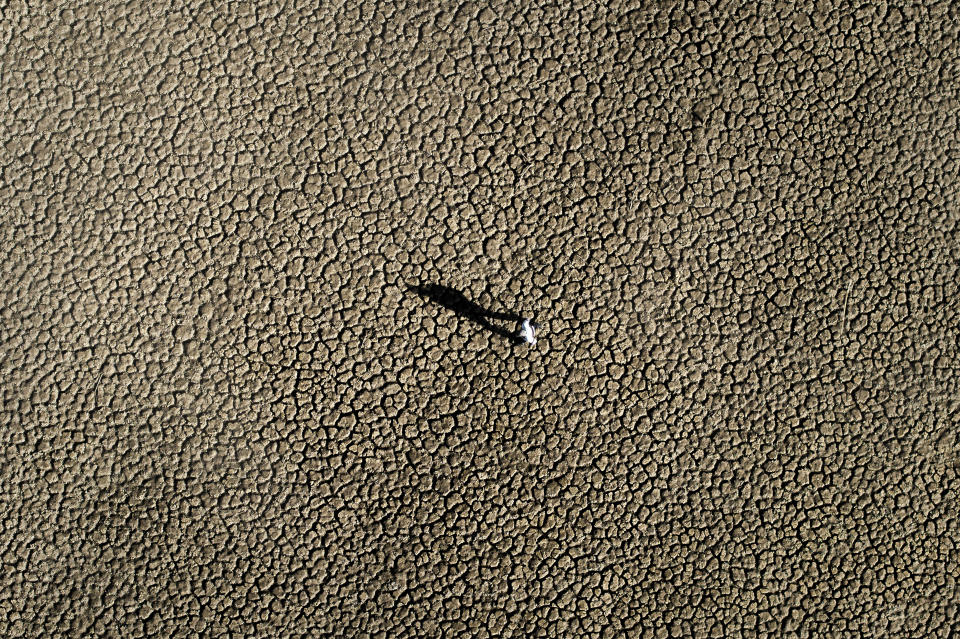 A man walks on the cracked ground of the Sau reservoir, which is only at 5 percent of its capacity, in Vilanova de Sau, about 100 km (62 miles) north of Barcelona, Spain, Friday, Jan. 26, 2024. Barcelona and the surrounding area of Spain's northeast Catalonia are preparing to face tighter water restrictions amid a historic drought that has shrunk reservoirs to record lows. Catalonia has recorded below-average rainfall for 40 consecutive months. Experts say that the drought is driven by climate change and that the entire Mediterranean region is forecast to heat up at a faster rate than many other regions in the coming years. (AP Photo/Emilio Morenatti)