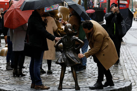 People look at a statue of a girl facing the Wall St. Bull, as part of a campaign by U.S. fund manager State Street to push companies to put women on their boards, in the financial district in New York, U.S., March 7, 2017. REUTERS/Brendan McDermid