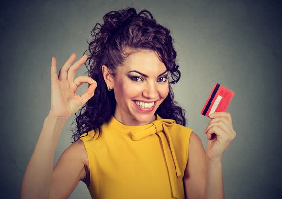 Happy woman holding credit card and showing ok sign