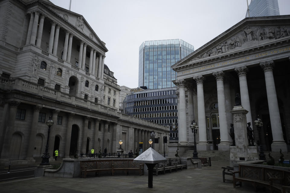 Security guards stand outside the Bank of England, left, next to the Royal Exchange, right, in the City of London financial district. Photo: Matt Dunham/AP