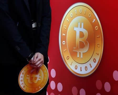 An attendant holds a bitcoin sign during the opening of Hong Kong's first bitcoin retail store February 28, 2014. REUTERS/Bobby Yip/Files