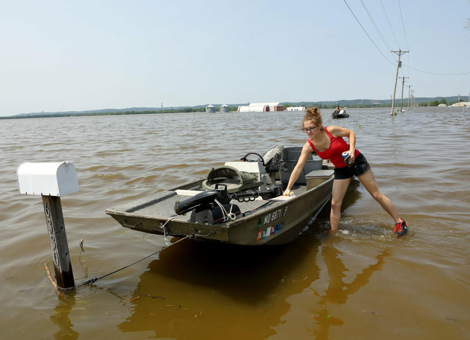 Emily Kientzel puts a cooler in her friend's boat as they prepare to take the boat out over floodwaters from the Mississippi River to his home outside of Portage des Sioux, Mo., Sunday, June 2, 2019. (David Carson/St. Louis Post-Dispatch via AP)