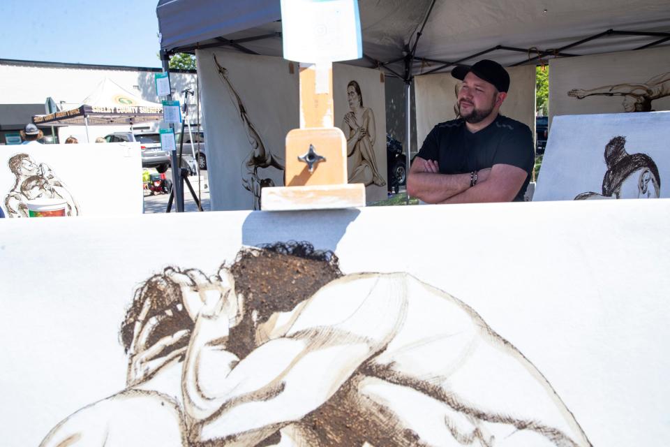 Chris Simmons stands surrounded by his artwork in his booth during the Cooper-Young Festival in Midtown Memphis, on Saturday, September 16, 2023.