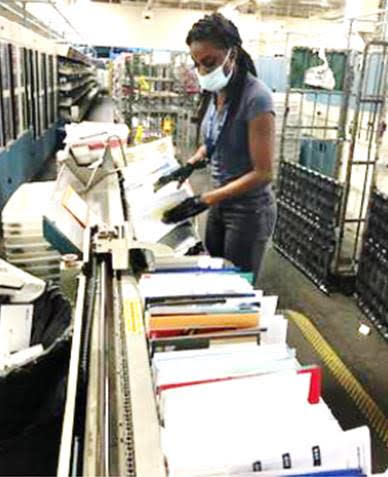 Mail Processor Nicole Bond wears a mask and gloves at the Miami Processing and Distribution Center. Via USPS