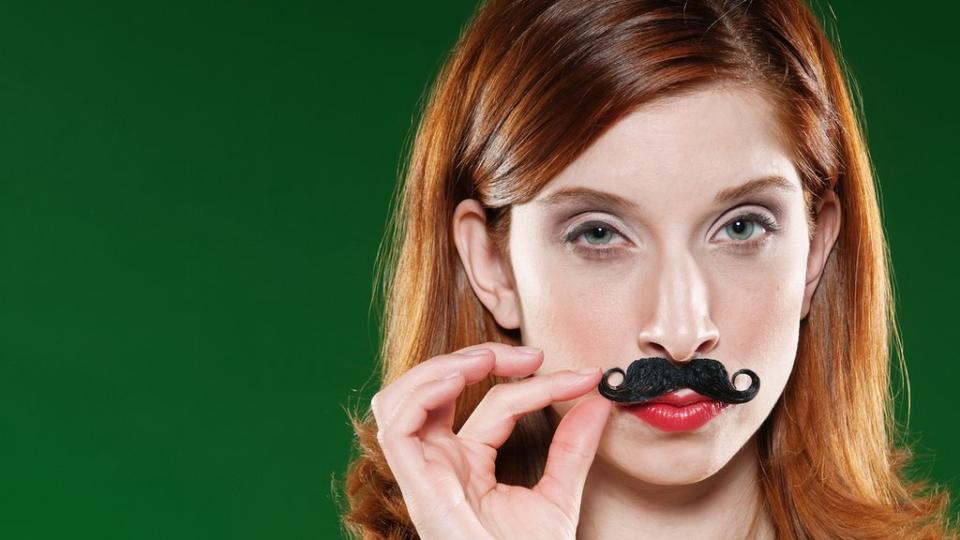 Chica poniéndose bigote postizo