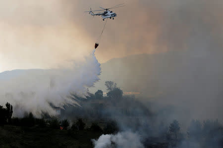 A firefighting helicopter makes a water drop as a wildfire burns near the village of Metochi, north of Athens, Greece, August 14, 2017. REUTERS/Alkis Konstantinidis