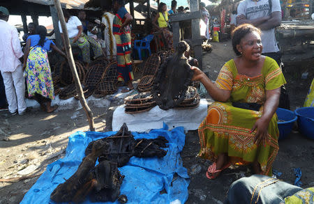 A vendor calls for clients as she holds smoked monkey meat and a variety of bushmeat at an open air market during the vaccination campaign aimed at beating an outbreak of Ebola in the port city of Mbandaka, Democratic Republic of Congo May 23, 2018. REUTERS/Kenny Katombe