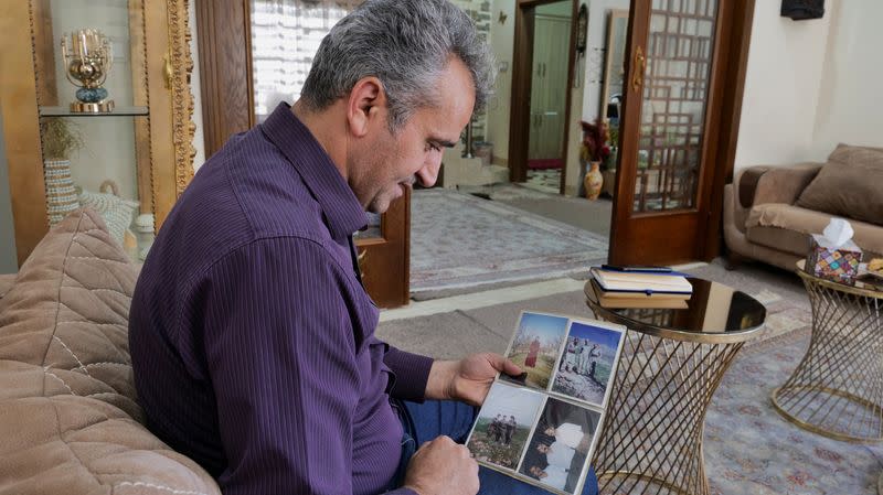 Khaled Abdullazade looks at pictures of himself, when he was in the Peshmerga of a Kurdish Iranian opposition group, in Erbil