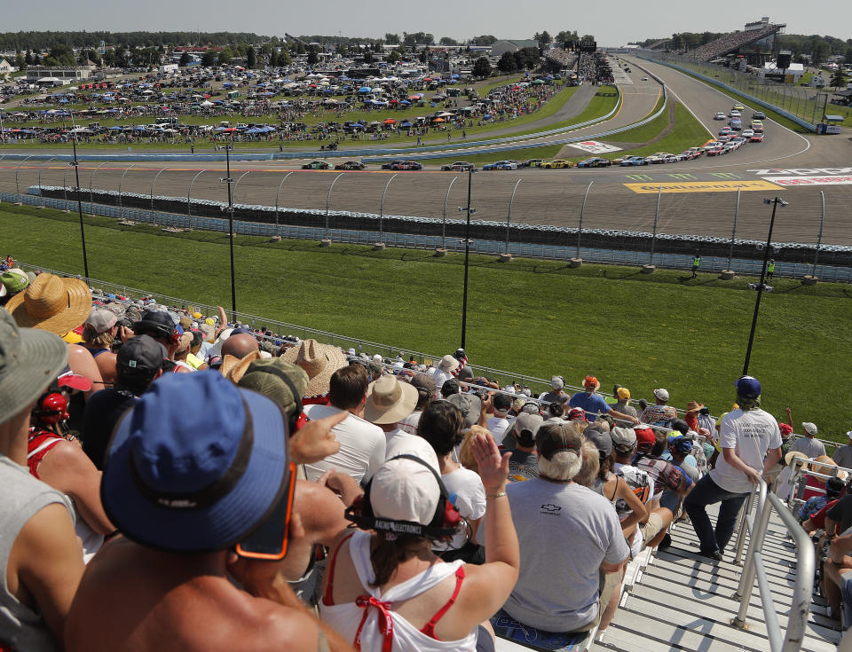 Spectators watch as drivers come around Turn 1 during a restart after a caution during a NASCAR Cup Series auto race, Sunday, Aug. 5, 2018, in Watkins Glen, N.Y. (AP Photo/Julie Jacobson)