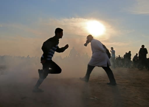 Palestinians run for cover from tear gas during clashes near the border between Israel and Khan Yunis in the southern Gaza Strip on November 9, 2018