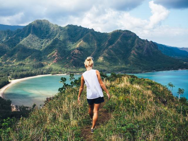 Woman hiker on a mountain trail overlooking the ocean in Hawaii