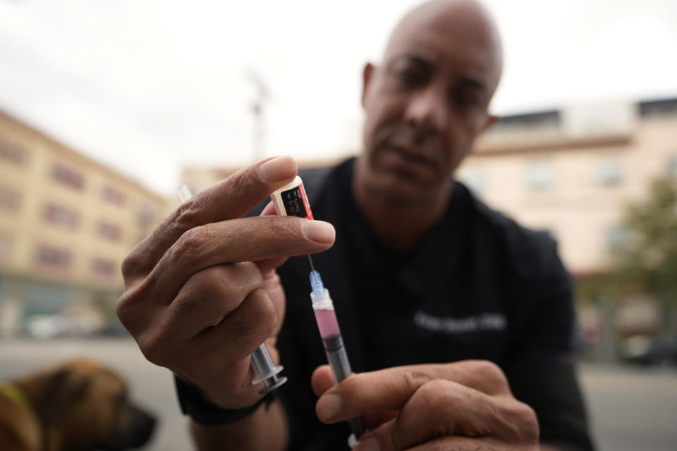Dr. Kwane Stewart prepares a rabies vaccine for homeless people's dog in the Skid Row area of Los Angeles on Wednesday, June 7, 2023. “The Street Vet,” as Stewart is known, has been supporting California's homeless population and their pets for almost a decade. (AP Photo/Damian Dovarganes)