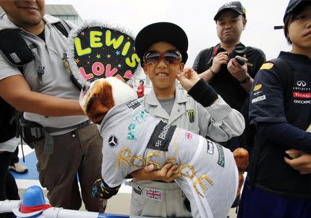 A fan dressed up as Mercedes Formula One driver Lewis Hamilton of Britain waits to meet drivers with a toy of Hamilton's bulldog Roscoe at the Suzuka circuit in Suzuka, western Japan, October 2, 2014, ahead of Sunday's Japanese F1 Grand Prix. REUTERS/Toru Hanai