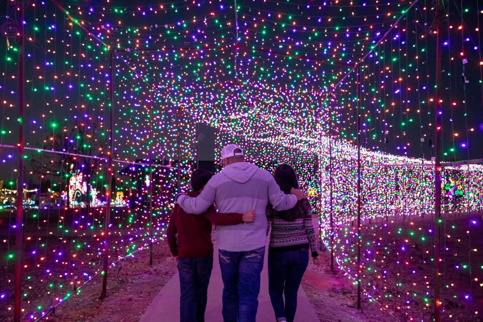 People walk through Yukon’s Christmas in the Park, billed as the state's largest drive-thru light display.