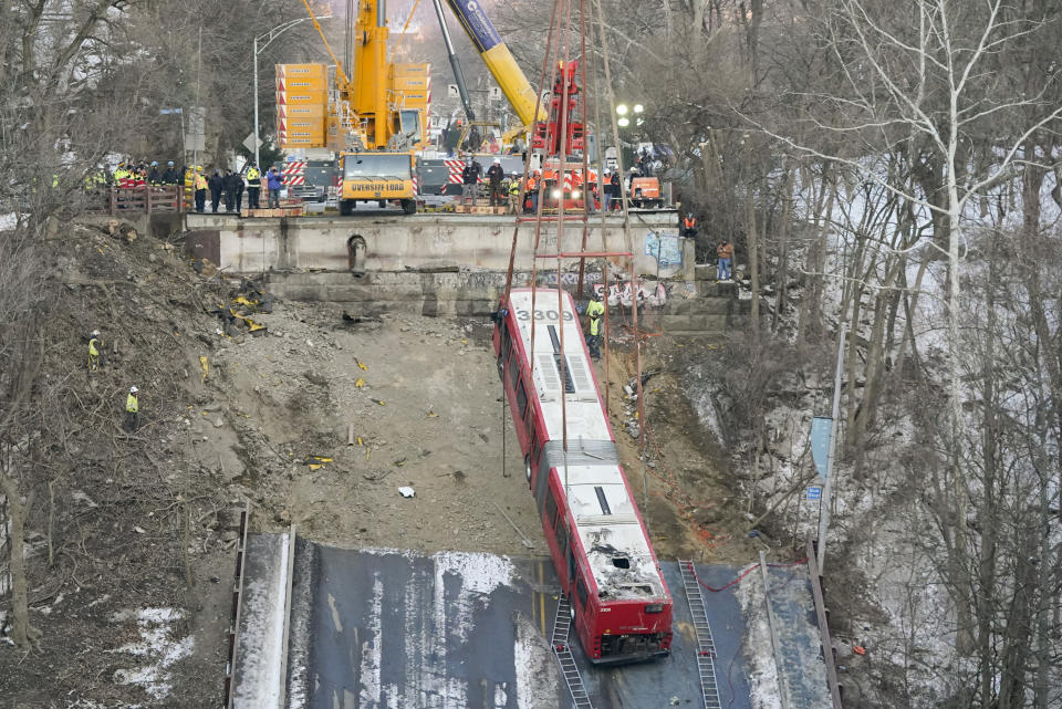 Cranes lift the bus that was on a bridge when it collapsed Friday during the recovery process on Monday Jan. 31, 2022 in Pittsburgh's East End. (AP Photo/Gene J. Puskar)