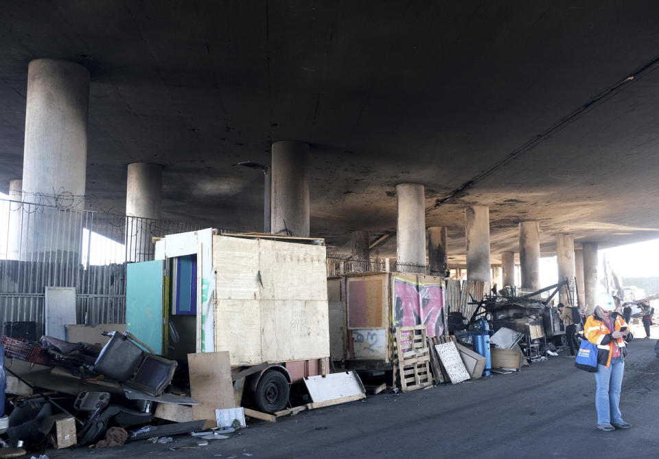 Part of a burned homeless encampment is shown as crews continue to clear debris and shore up a stretch of Interstate 10, Tuesday morning Nov. 14, 2023, in Los Angeles. It will take at least three weeks to repair the Los Angeles freeway damaged in an arson fire, the California Gov. Gavin Newsom said Tuesday, leaving the city already accustomed to soul-crushing traffic without part of a vital artery that serves hundreds of thousands of people daily. (Dean Musgrove/The Orange County Register via AP)