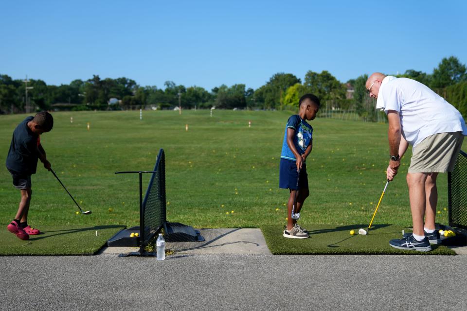 Volunteer coach Allan Dierker, of Union Township, gives a few tips to Larry C. Hodge, 8, of Silverton, during a July junior golf clinic hosted by Reaching Out For Kids, Inc. at Avon Fields in Avondale.