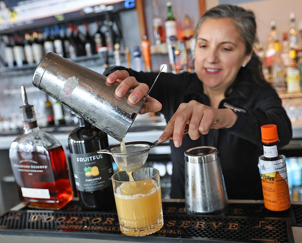 Bartender Jessica Rohrick adds smoke to a "Roots" cocktail, made with Woodford Reserve bourbon, pineapple liqueur and orange bitters at The Tree on Washington Street in Braintree, on Monday, April 1, 2024.