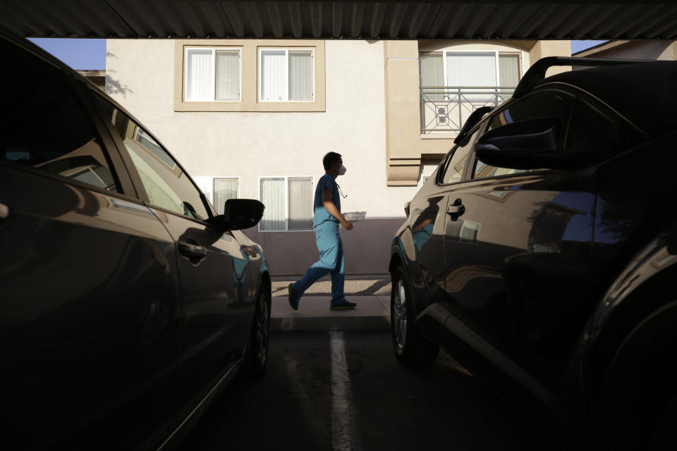 Dr. Tien Vo carries food for a woman quarantining in her apartment after testing positive for the coronavirus Thursday, July 23, 2020, in Calexico, Calif. Many in Imperial Valley live in crowded, multi-generation households that spread the virus quickly. Venus Nguyen, 35, Vo's wife and a nurse at Vo Medical Center, says, "One person does the cleaning, one person does the cooking, one person does the baby-sitting." (AP Photo/Gregory Bull)