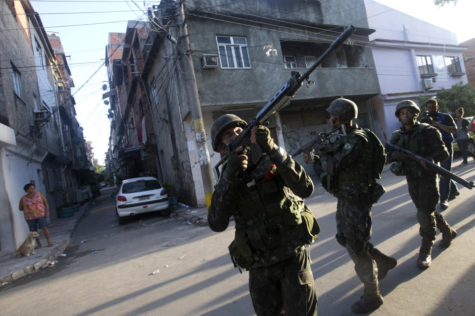 Army soldiers take position during an operation to occupy the Mare slum complex in Rio de Janeiro, Brazil, Saturday, April 5, 2014. More than 2,000 Brazilian Army soldiers moved into the Mare slum complex early Saturday in a bid to improve security and drive out the heavily armed drug gangs that have ruled the sprawling slum for decades. (AP Photo/Silvia Izquierdo)