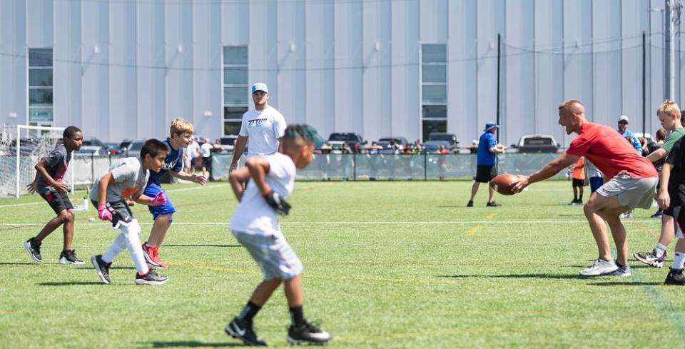 Troy Reeder (left) of the LA Chargers looks on during drills at a free NFL clinic for youths at Chase Fieldhouse, Friday, June 17, 2022