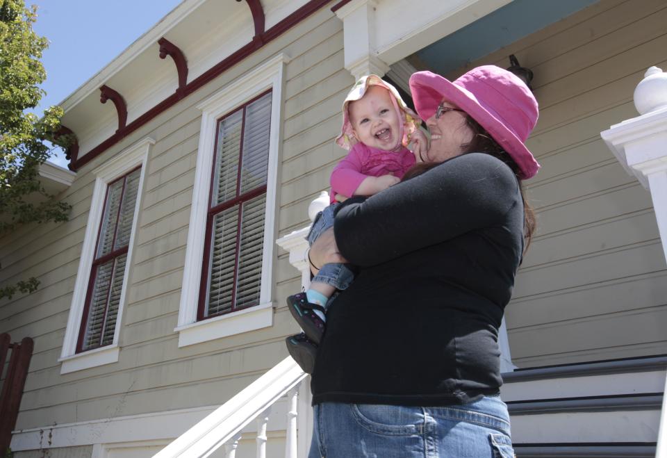 In this photo taken Tuesday, July 17, 2012, Sheila Dodson plays with her daughter, Emily, 1, outside their victorian home in Vallejo, Calif. In 2008 Vallejo declared bankruptcy, a move some in the community say was the city's only option to climb out of a financial hole. Dodson says that while the city coffers are poor, "it doesn't mean there's not opportunity." (AP Photo/Rich Pedroncelli)