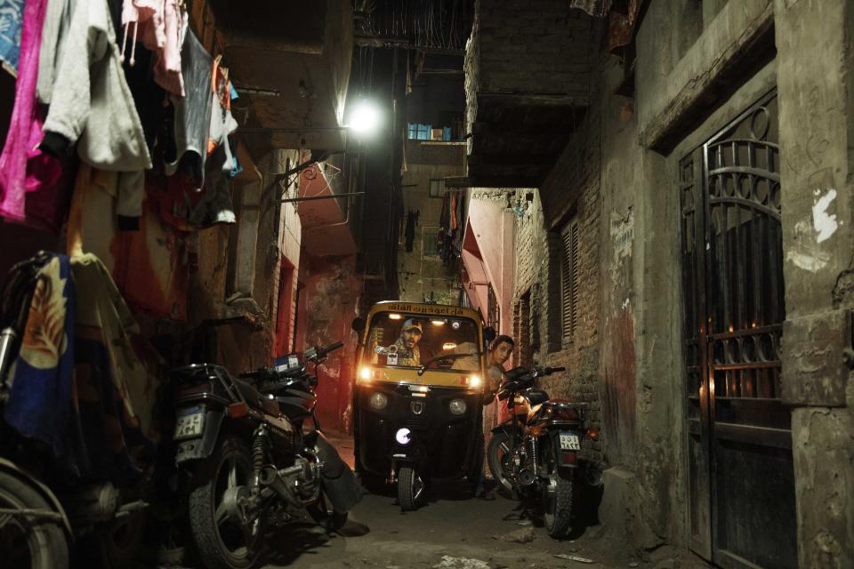 In this Nov. 19, 2019 photo, a driver tries to maneuver his tuk-tuk in a narrow alleyway of a slum in Cairo, Egypt. Motorized rickshaws known as tuk-tuks have ruled the streets of Cairo’s slums for the past two decades hauling millions of Egyptians home every day. Now the government is taking its most ambitious stand yet against the polluting three-wheeled vehicles: to modernize the neglected transport system, it plans to replace tuk-tuks with clean-running minivans. (AP Photo/Nariman El-Mofty)