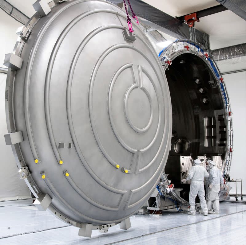 Workers at Carl Zeiss SMT stand in front of a vacuum chamber in Oberkochen