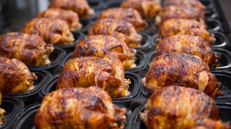 Rotisserie chickens in black trays 