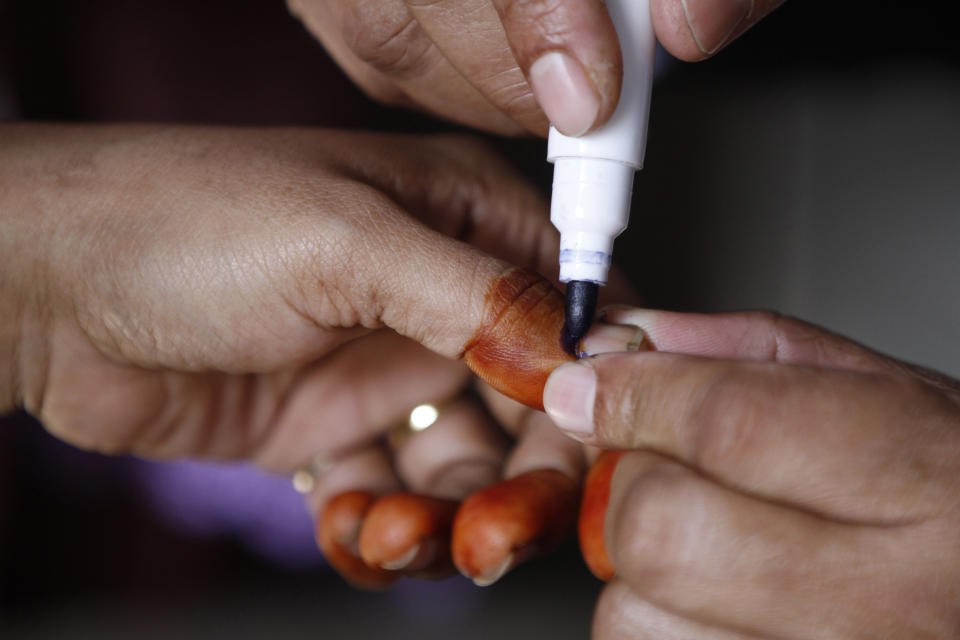 A Bangladeshi polling official places indelible ink on the finger of a woman before she casts her vote at a polling station in old Dhaka in Bangladesh, Sunday, Jan. 5, 2014. Police fired at protesters and more than 100 polling stations were torched in Sunday's general elections marred by violence and a boycott by the opposition, which dismissed the polls as a farce. (AP Photo/Rajesh Kumar Singh)