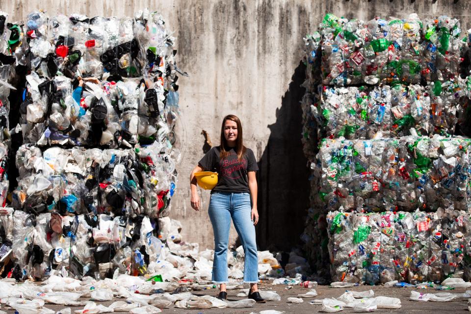 Katherine Shayne stands surrounded by bales of recyclable materials.