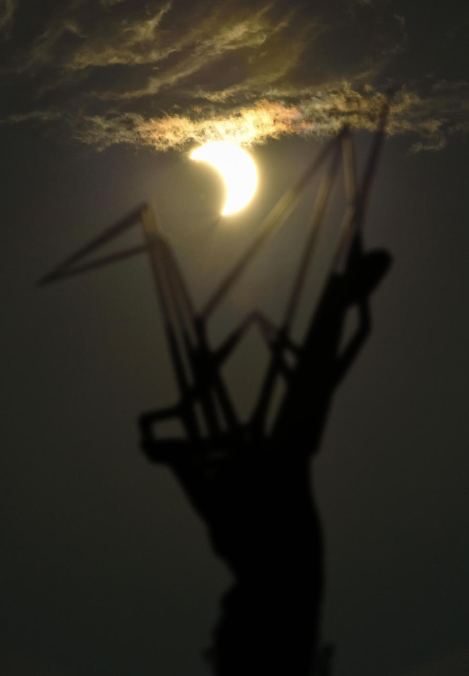 A partial solar eclipse is seen over the Children's Peace Monument at Hiroshima Peace Memorial Park in Hiroshima, western Japan Sunday, June 21, 2020. (Kyodo News via AP)