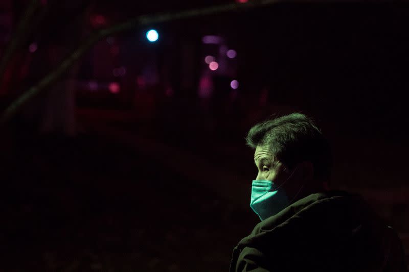 A man wearing a face mask walks in a park at night in Jiujiang