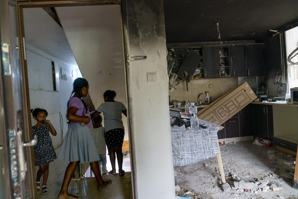 Residents walk past the apartment belonging to a Torah Nucleus Jewish family which was damaged in recent clashes between Arabs and Jews in the mixed Arab-Jewish town of Lod, central Israel, Wednesday, May 26, 2021. Many Arabs in Lod view the Torah Nucleus community with suspicion because of its ties with the West Bank settler movement. Some Arab residents refer to all of them collectively as "settlers." (AP Photo/David Goldman)