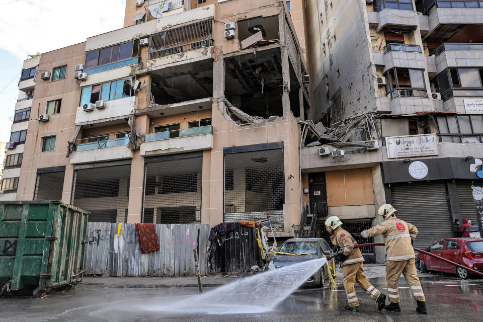 Lebanese civil defense members spray water on the street on Jan. 3, 2024, at the building that was hit the day before by a strike that killed Hamas deputy leader Saleh al-Aruri in Beirut. (Anwar Amro / AFP - Getty Images)