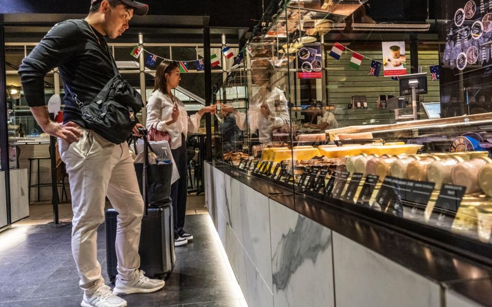 Tourists browse a traditional French cheese counter inside Les Halls de Lyon food market