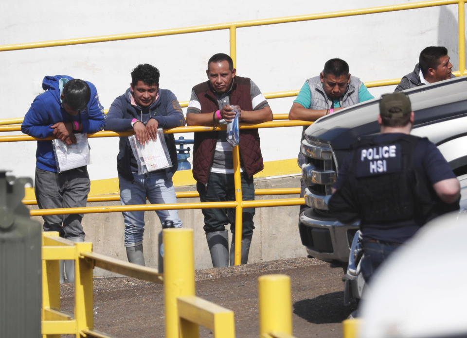 Handcuffed workers await transportation to a processing center following a raid by U.S. immigration officials at Koch Foods Inc., plant in Morton, Miss. | Rogelio V. Solis—AP