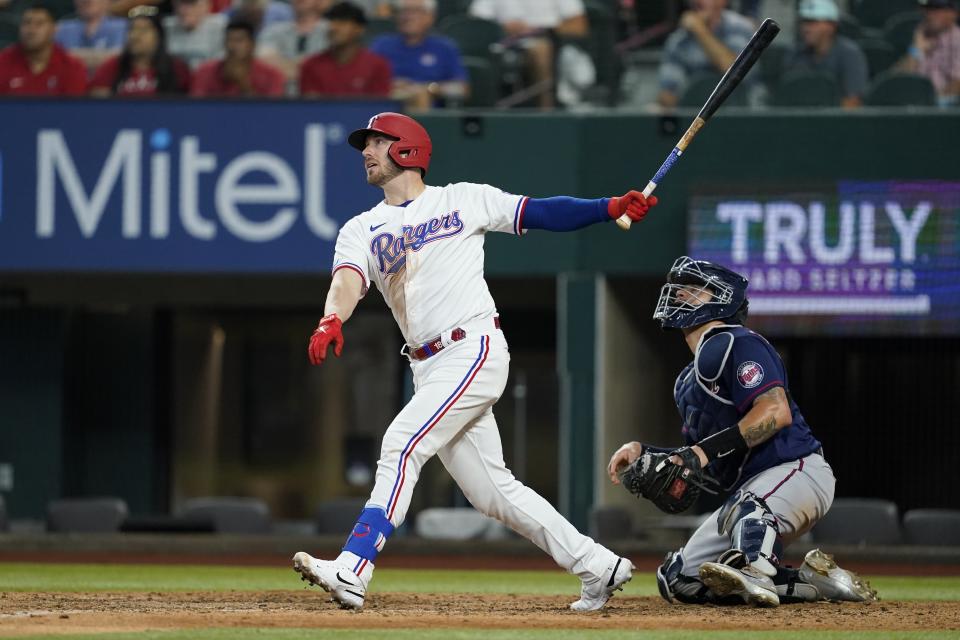 Texas Rangers' Mitch Garver watches his RBI single next to Minnesota Twins catcher Gary Sanchez during the eighth inning of a baseball game Saturday, July 9, 2022, in Arlington, Texas. (AP Photo/Tony Gutierrez)