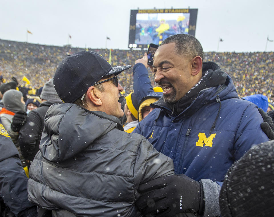 Michigan football coach Jim Harbaugh, left, is congratulated by basketball coach Juwan Howard, right, after an NCAA college football game against Ohio State in Ann Arbor, Mich., Saturday, Nov. 27, 2021. Michigan won 42-27. (AP Photo/Tony Ding)