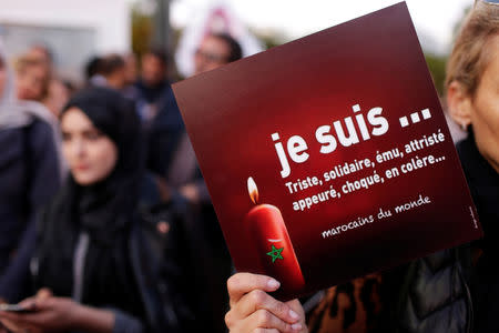A woman holds a sign "I am Sad, solitary, affected, shocked angry, saddened, frighten" in front of Denmark's embassy in Rabat to honour Maren Ueland from Norway and Louisa Vesterager Jespersen from Denmark, who were killed in Morocco, in Rabat, Morocco December 22, 2018. REUTERS/Youssef Boudlal