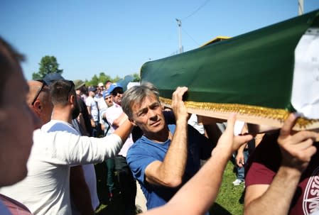 People carry a coffin during a mass funeral in the village of Hambarine