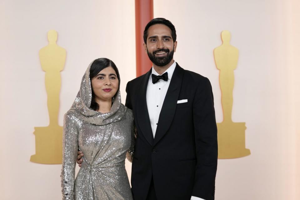 Malala Yousafzai, izquierda, y Asser Malik posan en la alfombra de los Oscars.