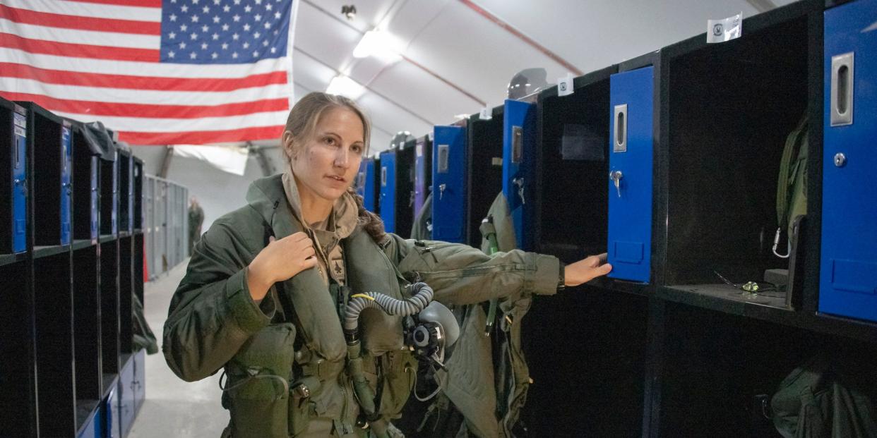 Air Force Capt. Emily Thompson, 421st Expeditionary Fighter Squadron pilot, dons flight equipment recently at the Aircrew Flight Equipment shop on Al Dhafra Air Base, United Arab Emirates