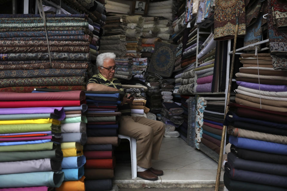 A shopkeeper works on his cellphone at his shop at the Qazvin old traditional bazaar some 93 miles (150 kilometers) northwest of the capital Tehran Iran, Wednesday, April 22, 2020. Iran's Revolutionary Guard said it put the Islamic Republic's first military satellite into orbit, dramatically unveiling what experts described as a secret space program with a surprise launch Wednesday that came amid wider tensions with the United States. (AP Photo/Vahid Salemi)
