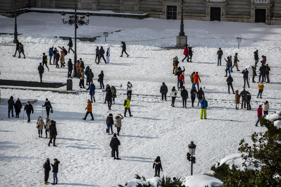 People walk through Oriente square covered with snow in downtown Madrid, Spain, Sunday, Jan. 10, 2021. A large part of central Spain including the capital of Madrid are slowly clearing snow after the country's worst snowstorm in recent memory. (AP Photo/Manu Fernandez)