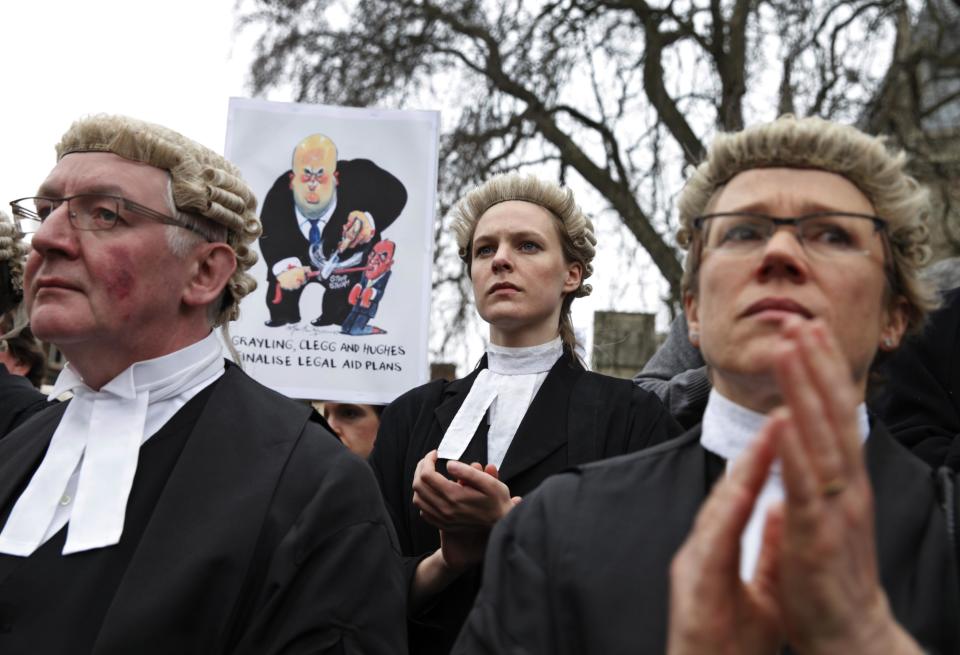Lawyers in their full court dress of wigs and gowns, participate in a rally to protest against legal aid cuts, across from the Houses of Parliament in central London, Friday, March 7, 2014. The protest coincides with a nationwide demonstration of non-attendance of lawyers which will affect hundreds of cases across the country. (AP Photo/Lefteris Pitarakis)