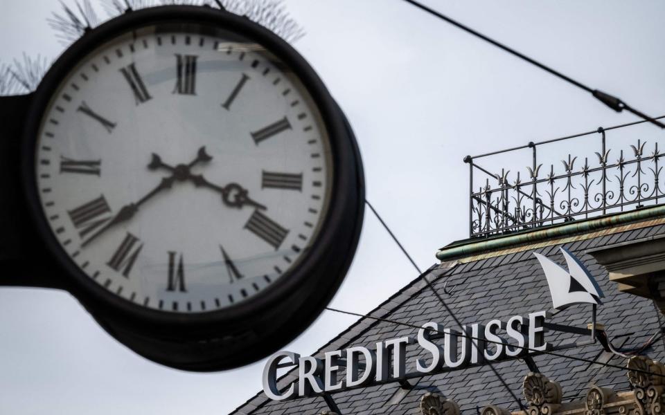 A sign of Credit Suisse is seen behind a clock at the headquarters of Switzerland's second-biggest bank in Zurich on March 18, 2023. - Switzerland's largest bank, UBS, is in talks to buy all or part of Credit Suisse, according to a report by the Financial Times. Credit Suisse came under pressure this week as the failure of two US regional lenders rocked the sector. (Photo by Fabrice COFFRINI / AFP) (Photo by FABRICE COFFRINI/AFP via Getty Images) - FABRICE COFFRINI/AFP via Getty Images