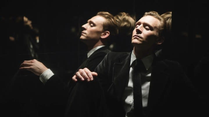 A man sits near a mirror in High-Rise.